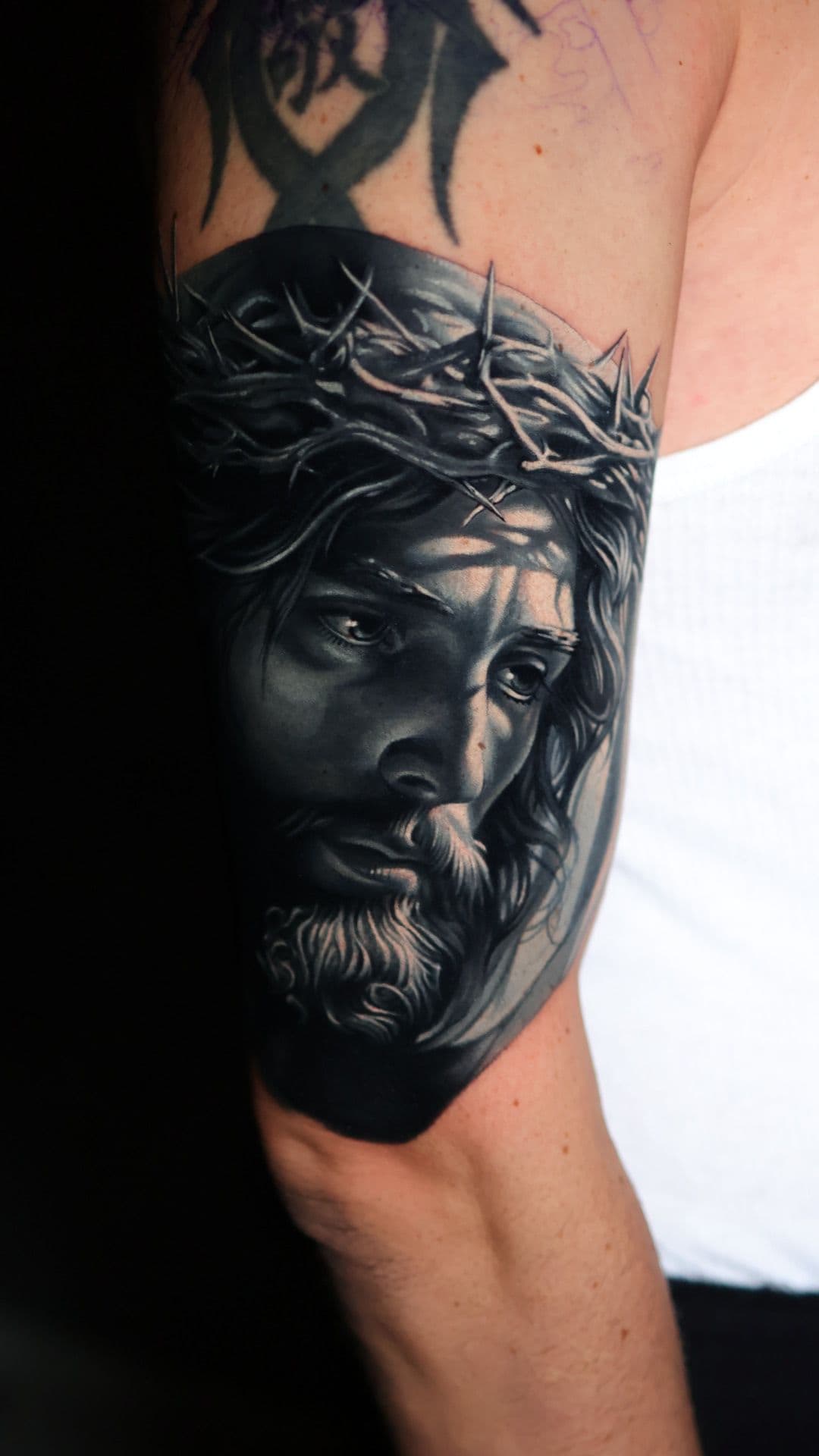 Cover-up-Tattoo: realistisches Porträt mit Dornenkrone über einem abgedeckten Vorgänger-Motiv – Blood Diamond Tattoo Ink.