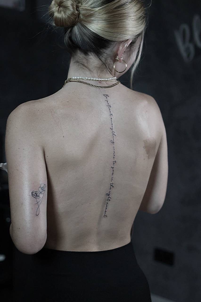 Fineline Tattoo – Schriftzug entlang der Wirbelsäule mit floralem Element – Blood Diamond Tattoo Ink.